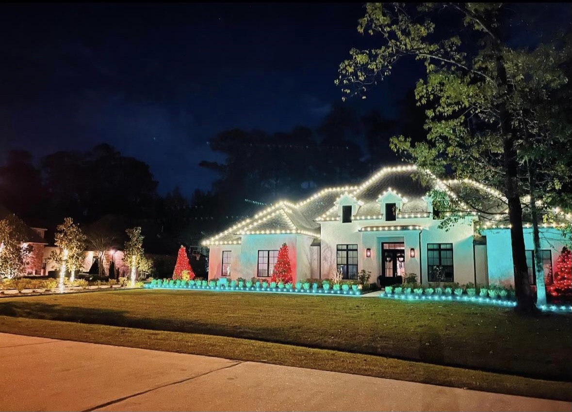 Residential Christmas lighting installation outlining a home roofline and landscaping at night
